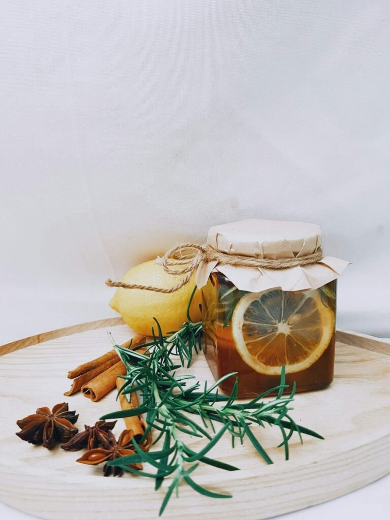 Glass jar of raw honey beside cinnamon sticks on a wooden surface, depicting natural sweeteners.